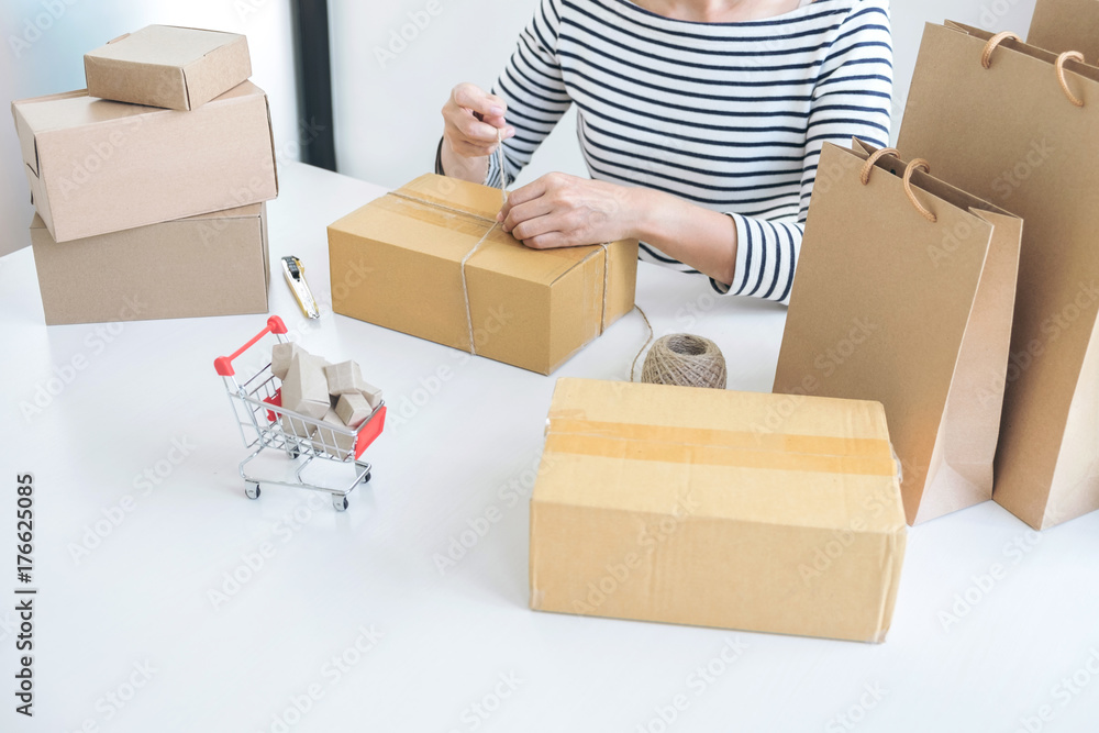 Fototapeta premium Internet online shopping concept, Young seller woman preparing package to be sent Mail transportation, service network connection market, technology on global, Order online for customer convenience