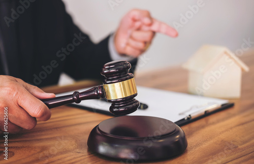 Male lawyer or judge hand's striking the gavel on sounding block, working at courtroom for decide home insurance, Law and justice concept, Settle a house dealing lawsuit