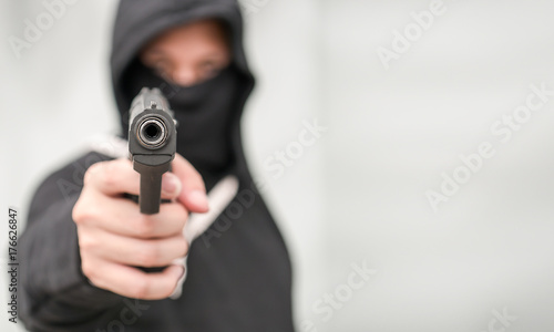 The male criminal in action of attacking with hand gun. Isolated on gray background. The concept of crime for presentation slide.