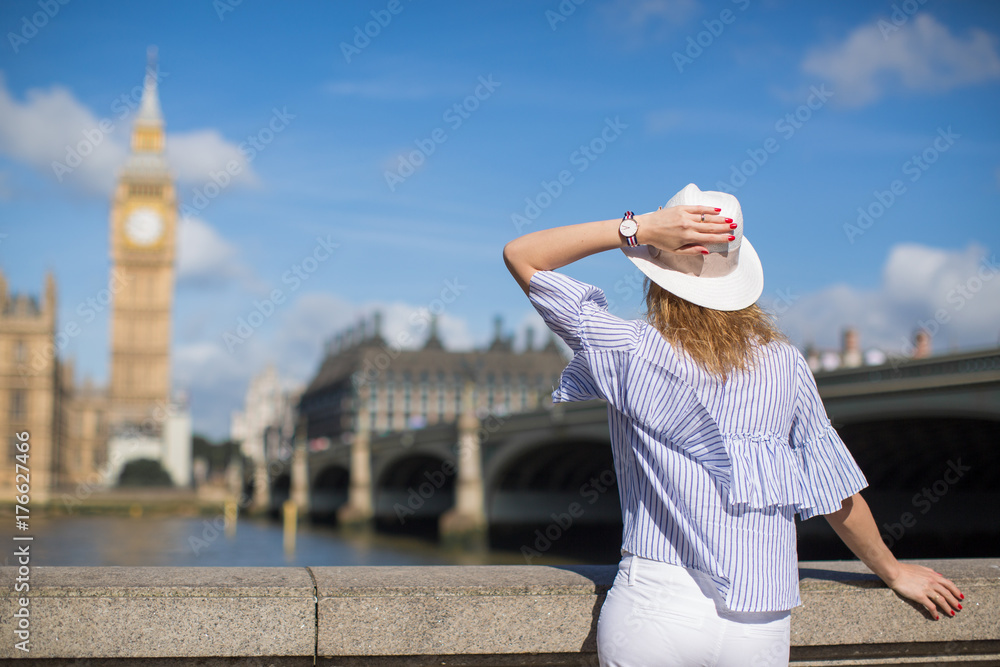 Back view of young stylish woman who standing outdoors and looking  on nature