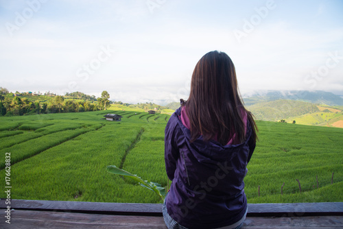 Woman tourism sitting on wood balcony to see view of green rice fields on terraces in Thailand at Ban Pa Pong Pieng in Mae chaem, Chaing Mai. 