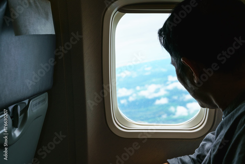 Middle-aged man looking out of airplane's window viewing Thailand's landscape below