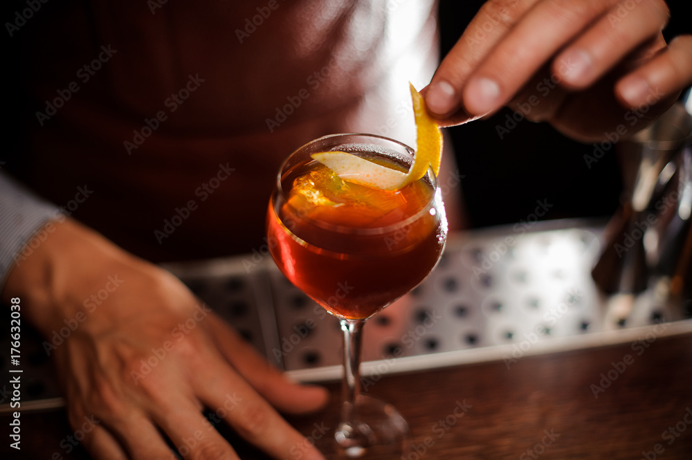 Bartender is decorating a cocktail with lemon zest