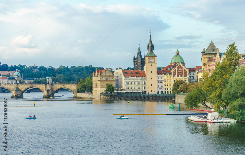 Obraz premium The Mill peninsula and the Charles Bridge in Prague in the Czech Republic at sunset. Boats on the Vltava River
