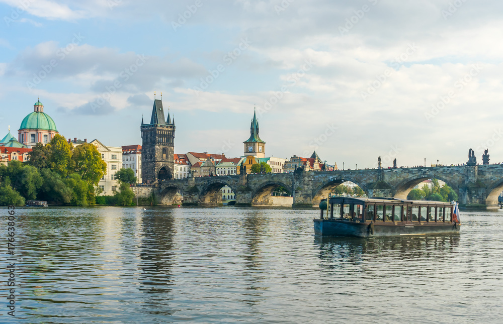 Charles Bridge in Prague in the Czech Republic. Catholic church of St. Franciszek of Serafin. Pleasure boats on the Vltava River
