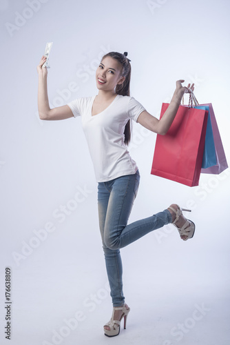 Woman hold the money in hand and shopping bags happily in purchases on a white background.Shopping and Business concept