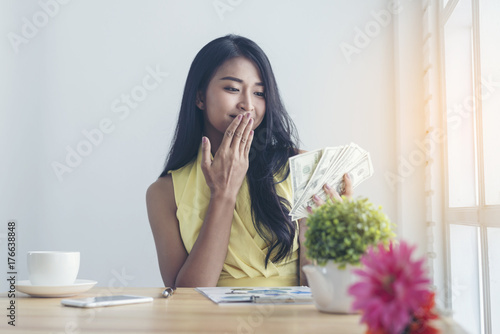 Casual business women are counting money happily from selling products online by phone with business documents on the table in the cafe