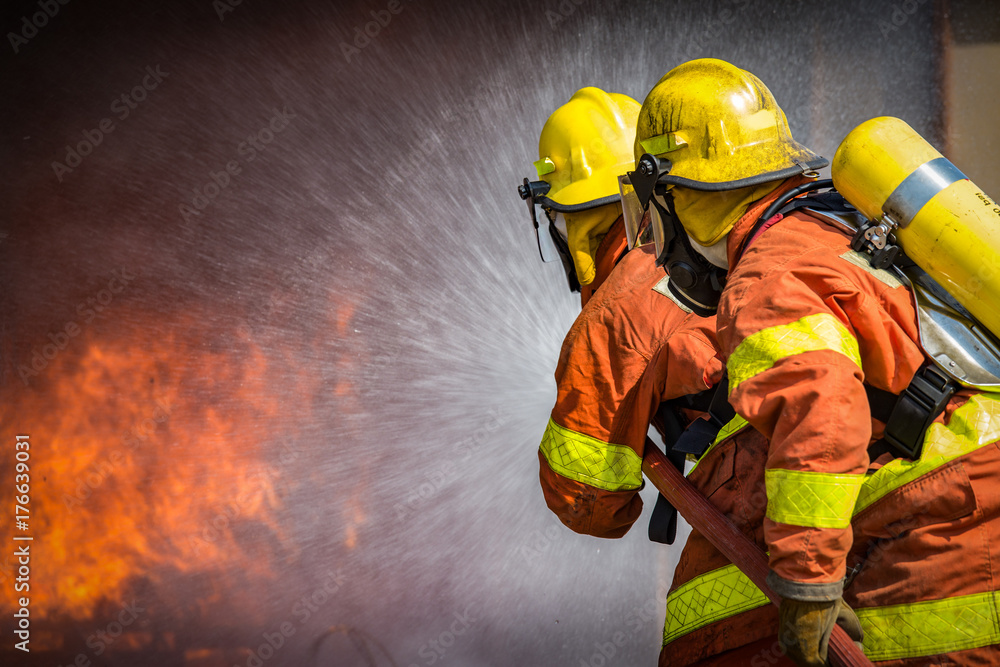 Fototapeta premium 2 firefighters spraying high pressure water to fire with copy space