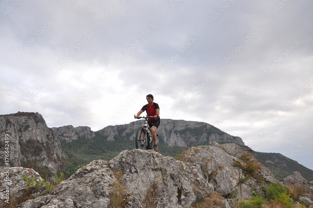 Young man riding a bike on rocks on the mountain, extreme riding bicycle off road on rocks
