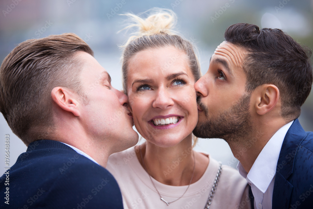 two young men kissing woman on her cheeks two young men kissing woman on her cheeks