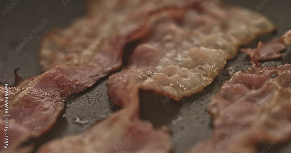 Pan with strips of fried bacon on stove Pan with strips of fried bacon on stove