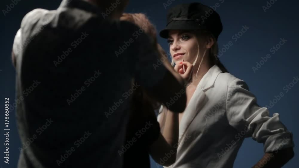 A make-up artist and a stylist work with a model in a black hat A make-up artist and a stylist work with a model in a black hat