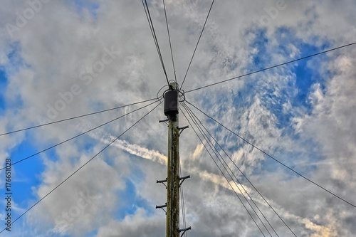 Overhead telecoms cables an wooden pole against the sky