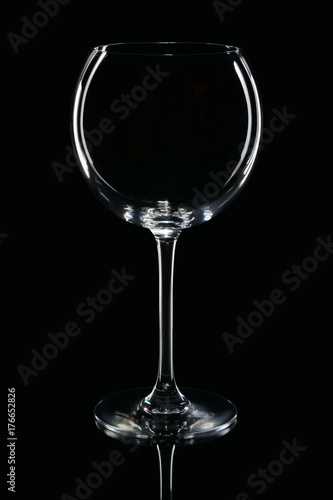 Empty round wine glass with reflection on black background