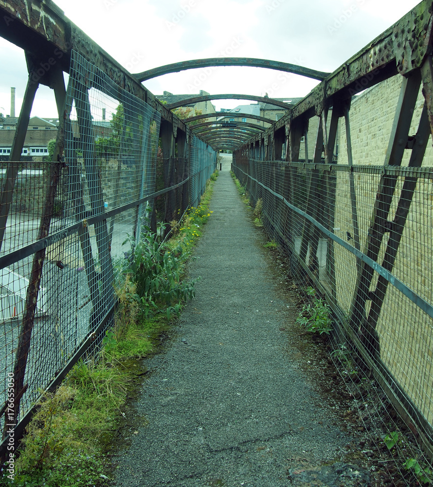 Fototapeta premium perspective view of an old rusting railway footbridge in halifax west yorkshire