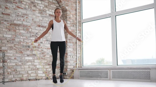 A woman of athletic build quickly jumps rope, the lady performs cardio exercises in the fitness club, she warms up the muscles before training photo