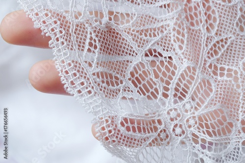 Фотография Beautiful delicate openwork white lace in hand
