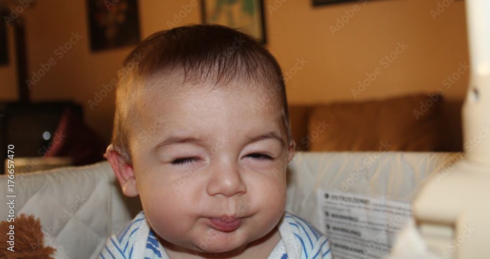 Naklejka premium five months old baby boy in the cot making funny faces