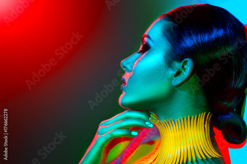 Fashion model woman in colorful bright lights with trendy make-up, manicure and haircut