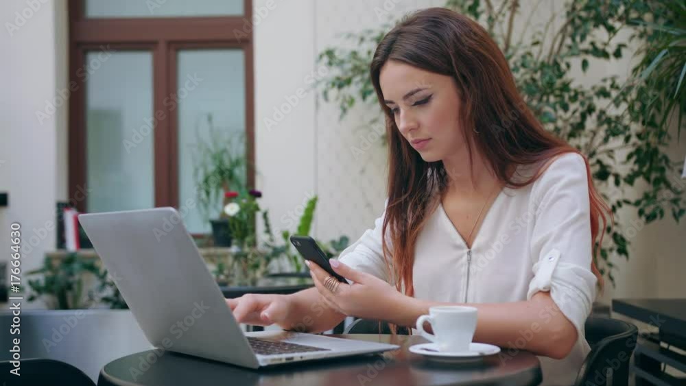 A beautiful girl using her mobile phone and a laptop in the room. Closeup shot. Soft focus. A beautiful girl using her mobile phone and a laptop in the room. Closeup shot. Soft focus.