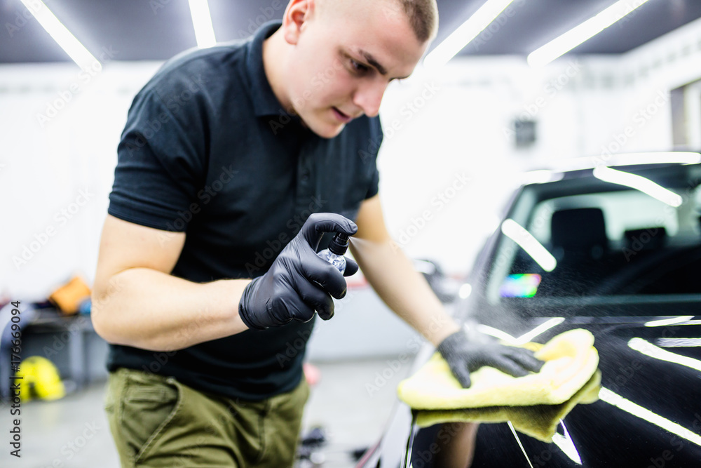 A man cleaning car with microfiber cloth, car detailing (or valeting) concept. Selective focus. A man cleaning car with microfiber cloth, car detailing (or valeting) concept. Selective focus.