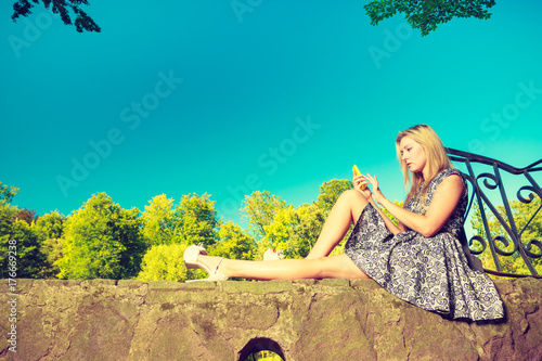 Woman sitting in park, relaxing and using phone