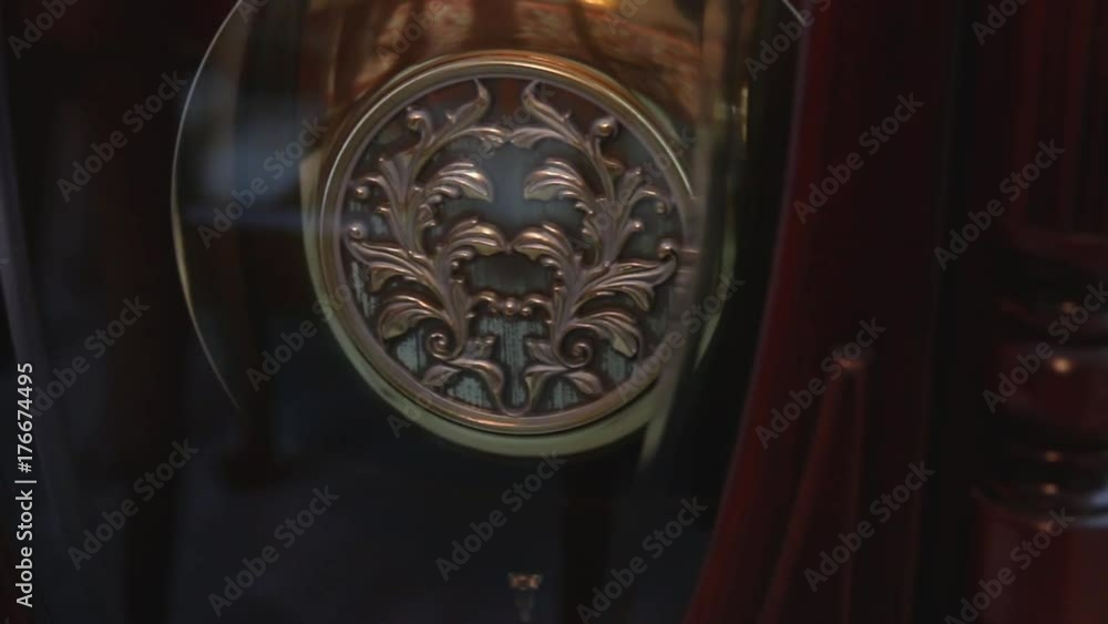 Decorative pendulum on a grandfather clock swinging back and forth
