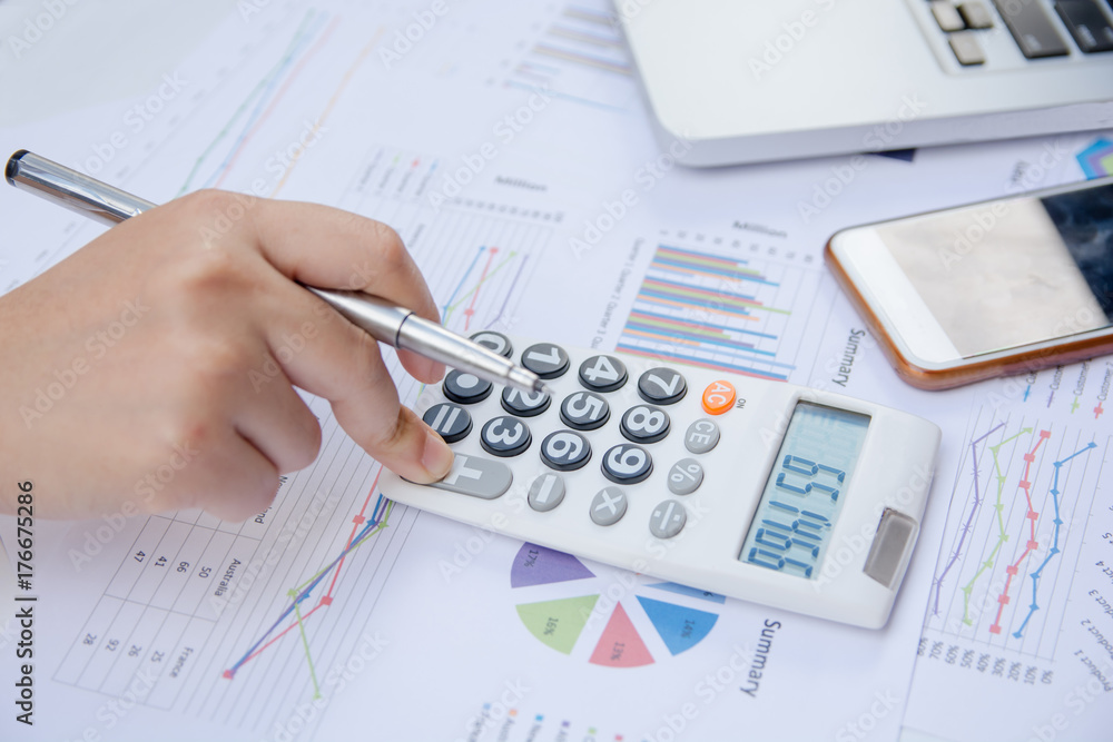 close up woman using calculator on paper graph data with doing finance at office. close up woman using calculator on paper graph data with doing finance at office.