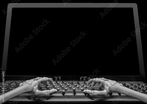 View of two skeleton hands typing on a keyboard in front of a blank computer screen ready for someone to fill with graphics or text.