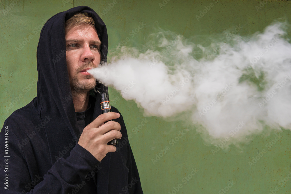 Man with vape. Young man smoking an electronic cigarette