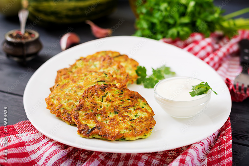 Zucchini pancakes with parsley on a wooden table. Zucchini pancakes with parsley on a wooden table.