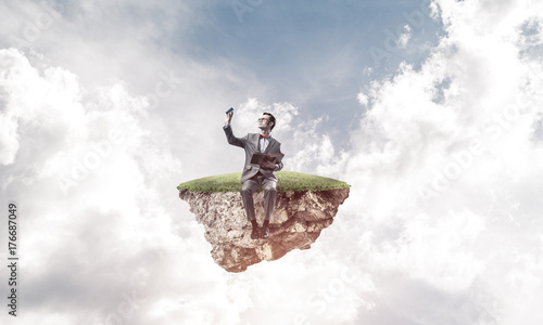 Young businessman or student floating in sky and studying the sc © adam121