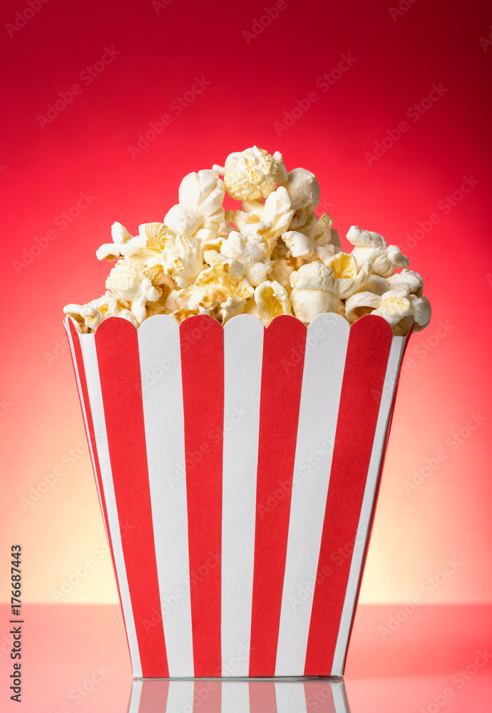 Salty popcorn in large square box on bright red.