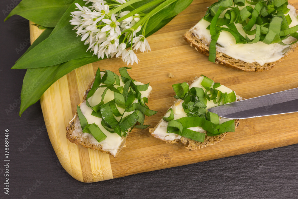 bread and butter with chopped wild garlic on wooden board bread and butter with chopped wild garlic on wooden board