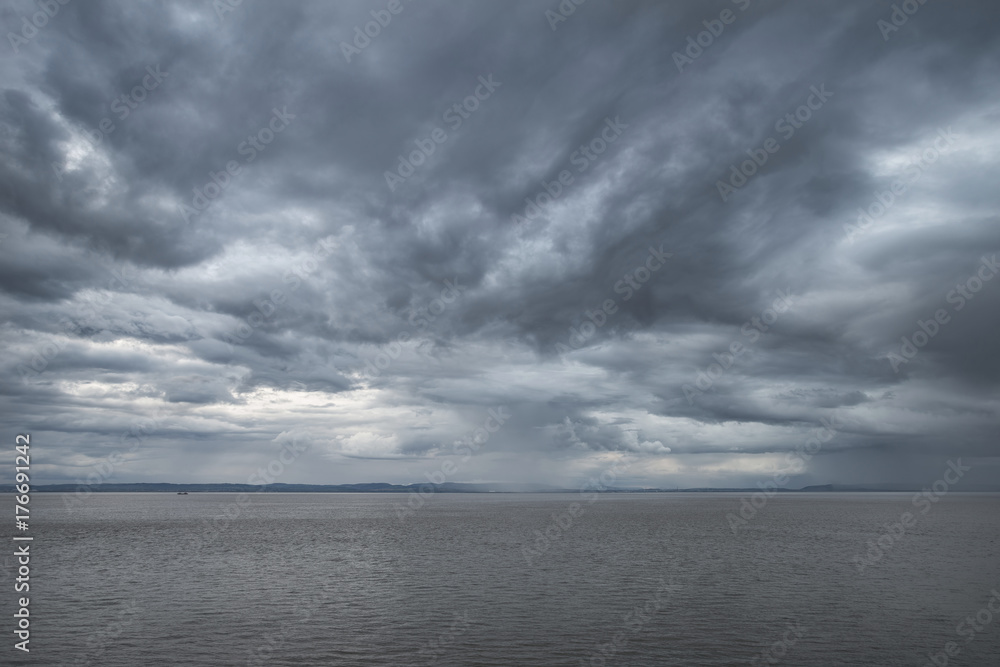 Landscape image of view out to sea with storm cloud sky overhead