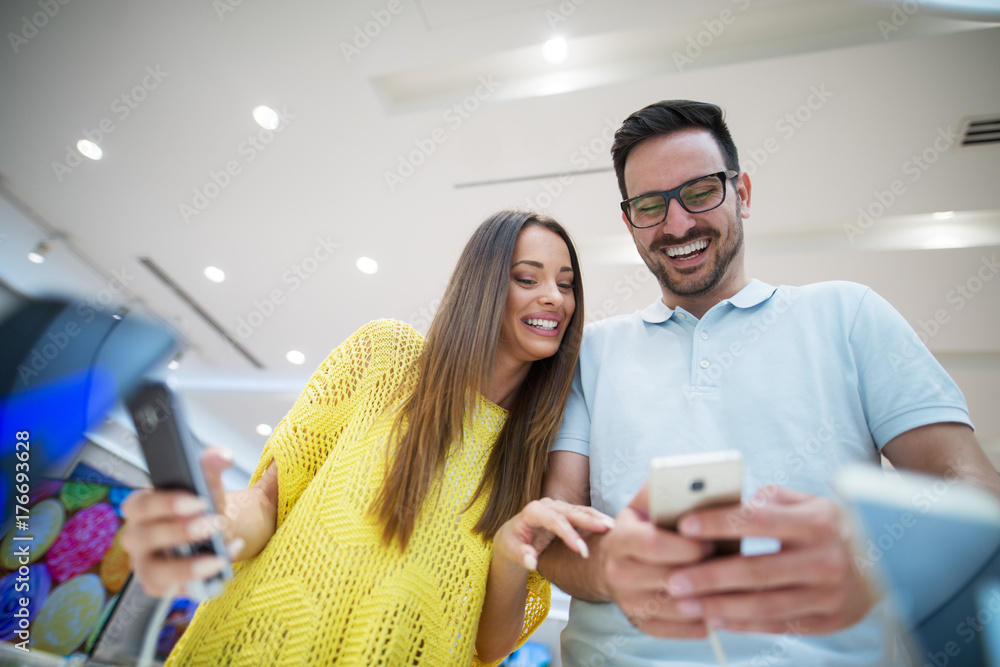 Buying new smart phone at tech store. Looking for a new peace of tech gadget. Couple in shopping. Buying new smart phone at tech store. Looking for a new peace of tech gadget. Couple in shopping.