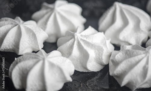 Close-up picture of meringues on a black plate  food background.