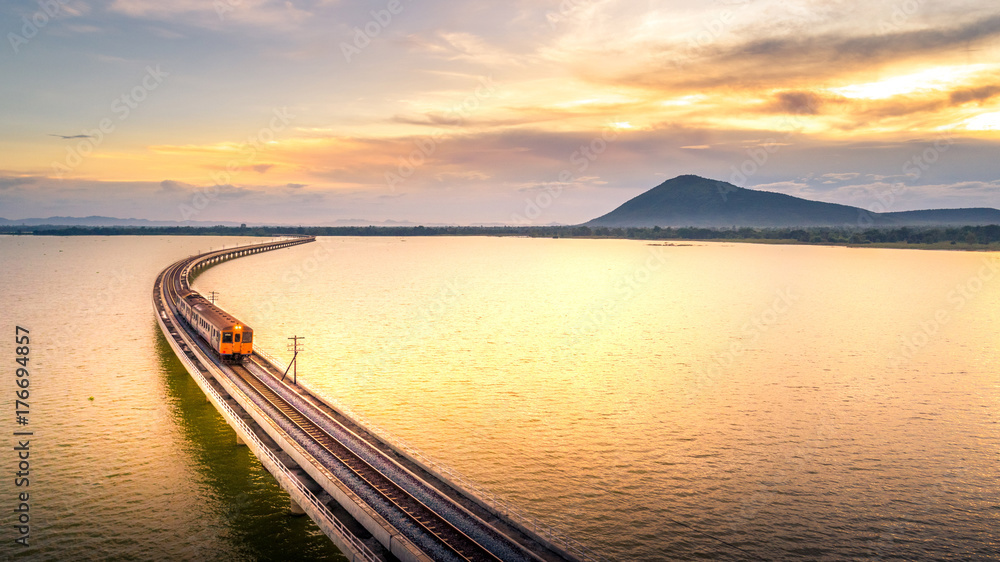 Obraz premium Aerial Photo The train is running on the bridge Over lake Pa Sak Dam Lopburi Thailand beautiful sunlight Golden hour