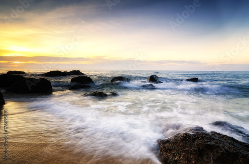 Travel and leisure concept  beautiful sea view scenery over stunning sunrise background.sunlight beam and soft wave hitting beach rocks