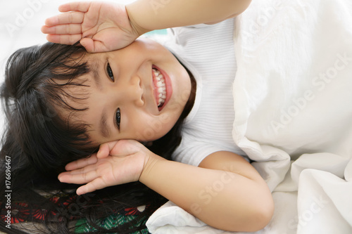 Asian children cute or kid girl sleep with open hand from eye for enjoy playing peekaboo or hide and seek with smile white teeth