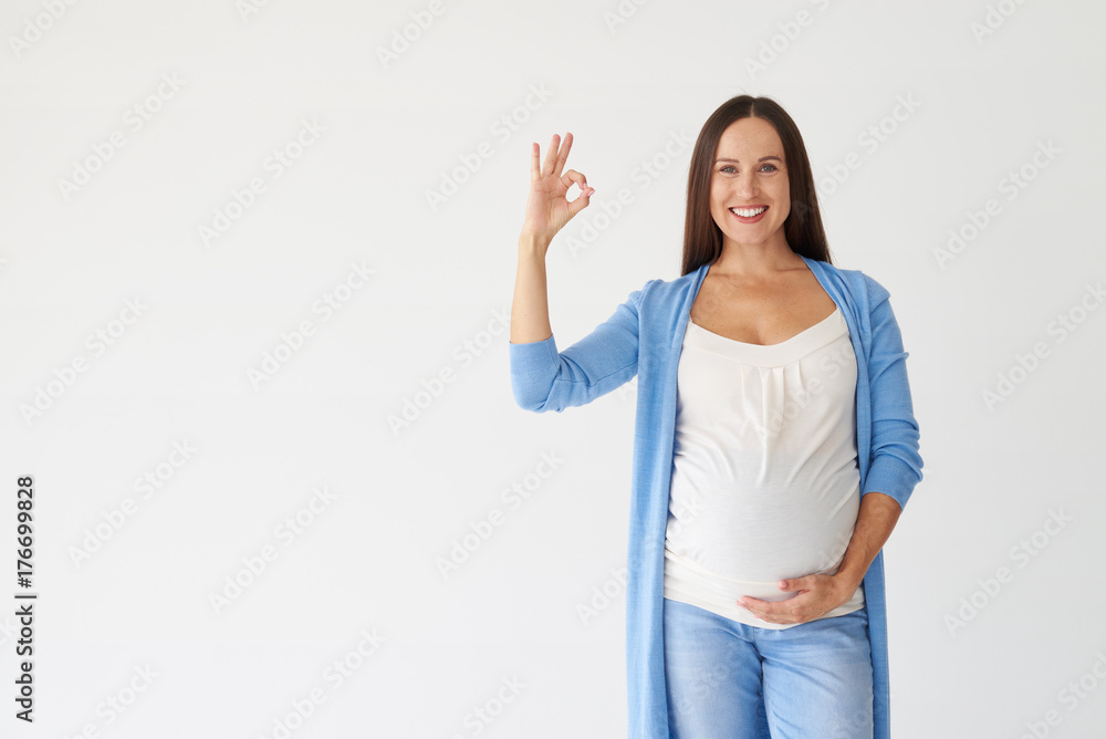 Young pregnant woman showing okay gesture isolated on white background Young pregnant woman showing okay gesture isolated on white background