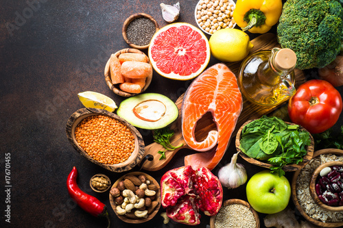 Balanced diet food background. Organic food for healthy nutrition  superfoods. Meat  fish  legumes  nuts  seeds  greens  oil and vegetables. Top view on dark stone table.