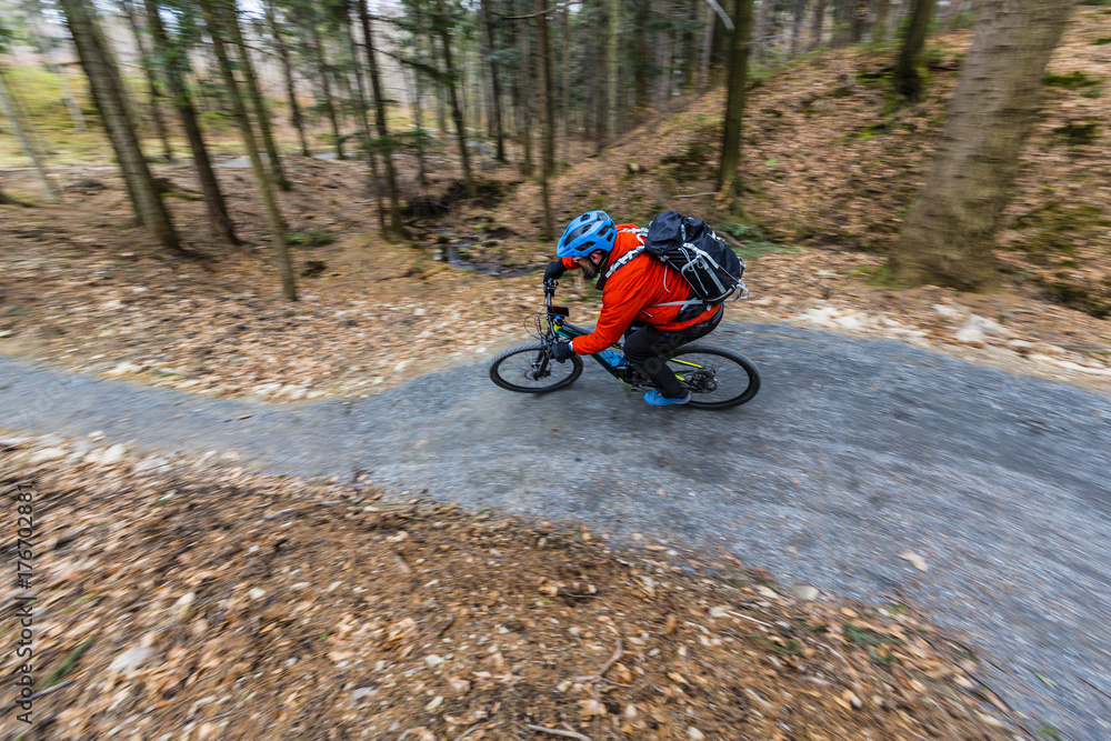 Obraz premium Mountain biker riding on bike in early spring mountains forest landscape. Man cycling MTB enduro flow trail track. Outdoor sport activity.