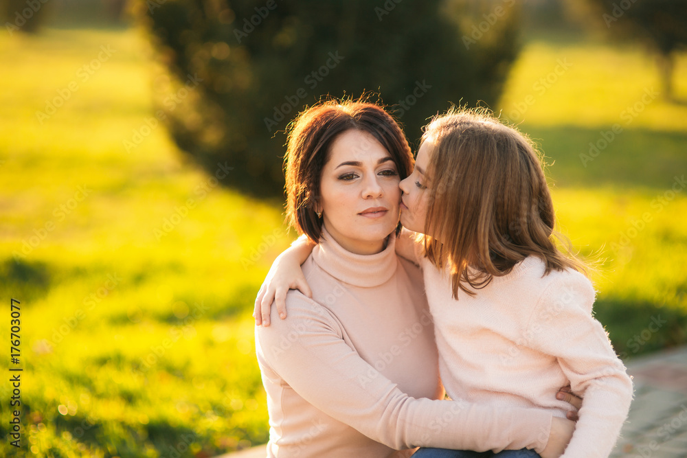 Little girl with mother walking in the park in autumn