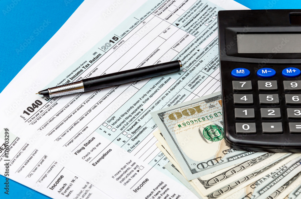 Tax form with calculator, money and pen on a blue background. Business concept. Top view. Tax form with calculator, money and pen on a blue background. Business concept. Top view.