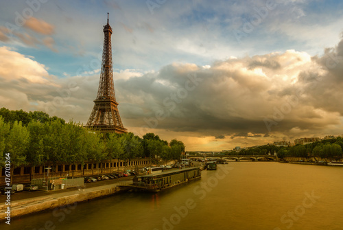 The Eiffel Tower in Paris, France at sunset. Scenic stylized skyline with the river Seine and dramatic clouds. Colourful travel background.
