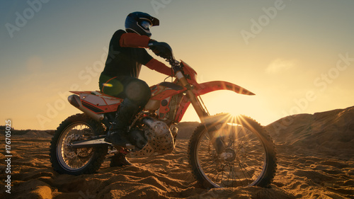 Low Angle Shot of the Professional Motocross Driver Sitting on His FMX Motorcycle Twisting Full Throttle Handle and Starting to Ride This Extreme Off-Road Terrain Track