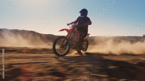 Side View Footage of the Professional Motocross Motorcycle Rider Driving on the Dune. It's Sunset and Track is Covered with Smoke/ Dust/ Dirt. Blur motion.