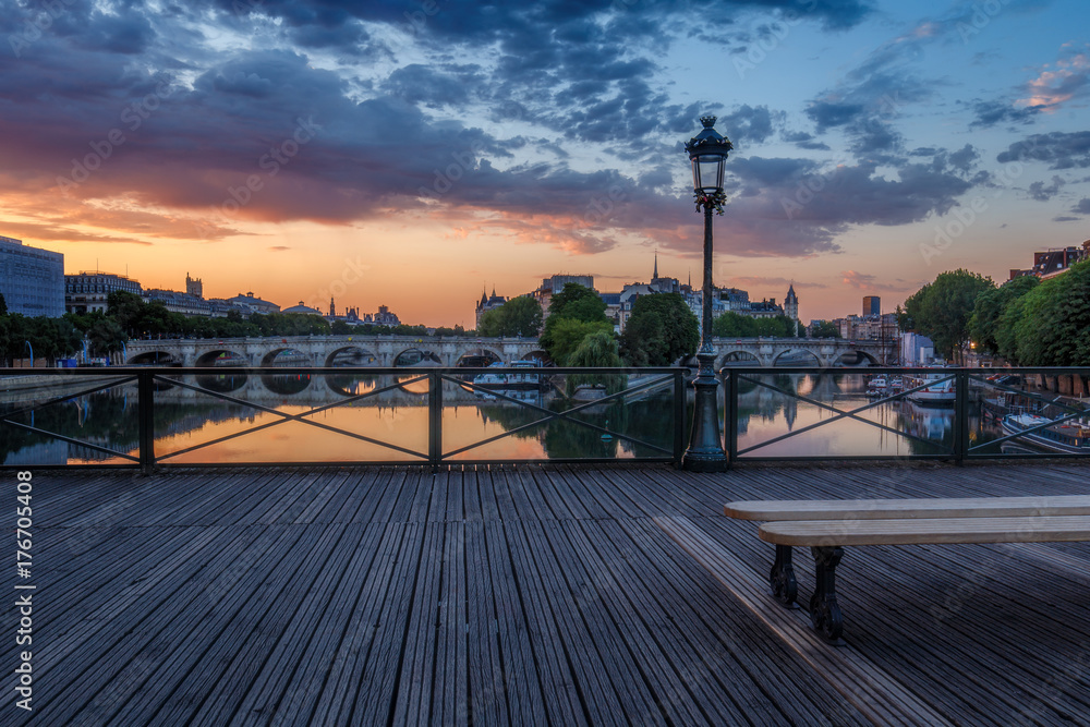 Sunrise over Paris, France with Pont des Arts and the river Seine. Colourful skyline with dramatic clouds.