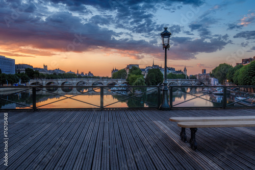 Sunrise over Paris, France with Pont des Arts and the river Seine. Colourful skyline with dramatic clouds.